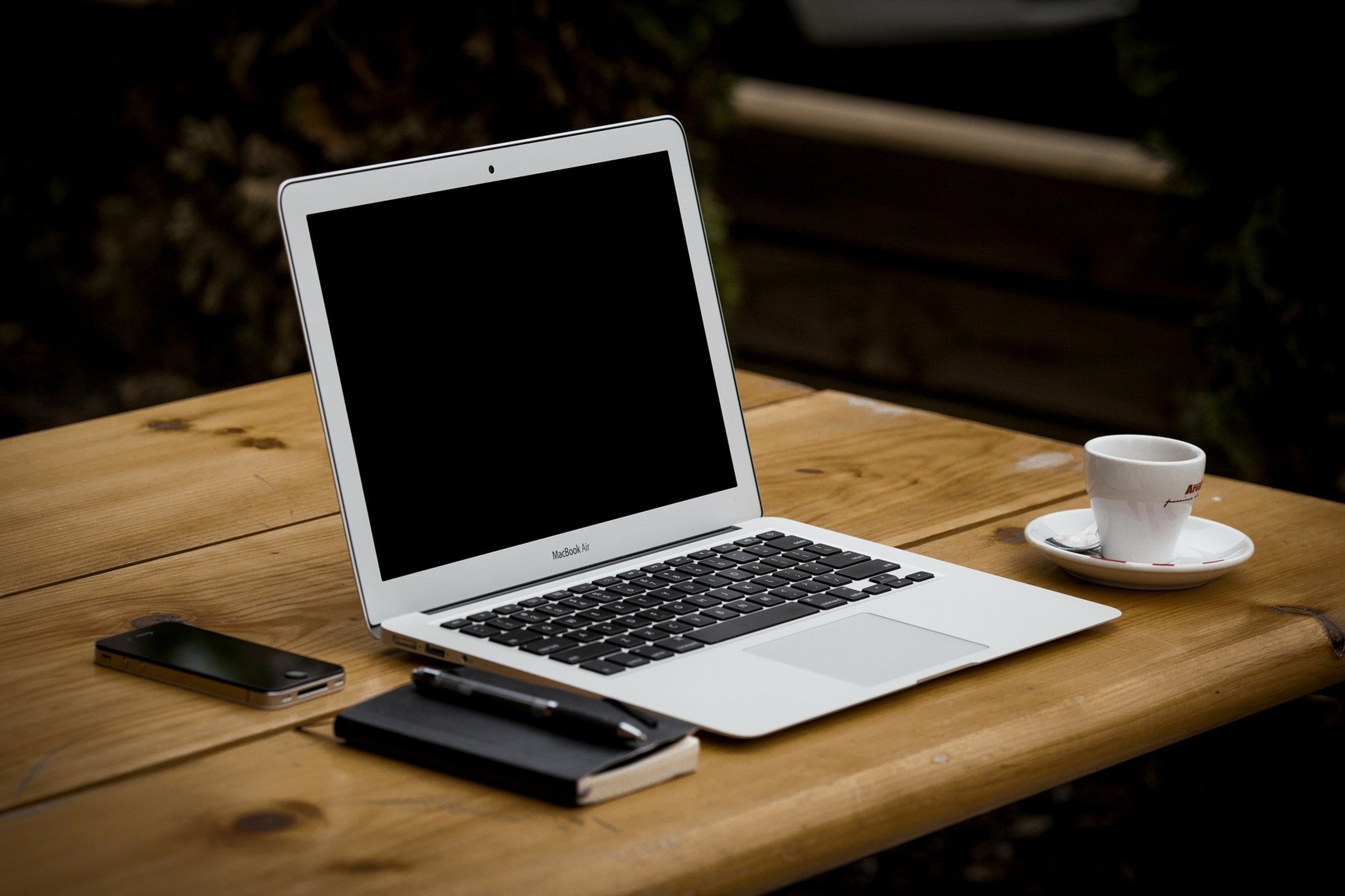 Laptop mit Tasse, Block, Stift und Handy